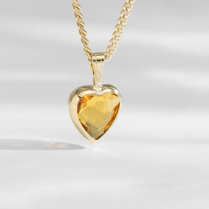Detailed macro shot of a heart-shaped yellow topaz pendant in a golden frame