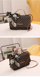 Close-up of vintage brown monogram handbag with decorative silk scarf and metal logo