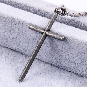 Macro shot of punk style cross pendant with distressed metal texture on grey velvet