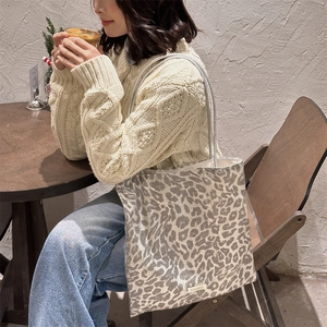 Detail of leopard print canvas tote bag with woven label in a cozy winter setting