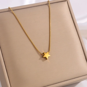 Macro detail of gold-plated star pendant necklace resting on a beige velvet jewelry box