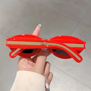 Close-up of red cat-eye sunglasses with detailed gold metal accents on the temple