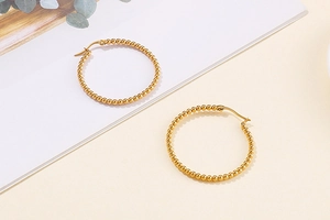 Detail of golden hoop earrings featuring a beaded design with 45-degree top view