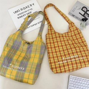 Close-up of lightweight plaid canvas tote bags with embroidered text and minimalist patterns