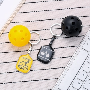 Close-up of yellow and black pickleball paddle keychains on a desk background