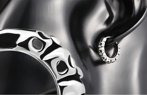 Macro detail of punk skull relief on silver stainless steel hoop earring for men