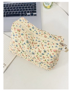 Borsa cosmetica trapuntata floreale con etichetta 'Little House' su scrivania bianca