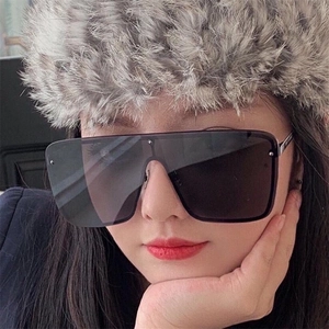 Close-up of oversized square sunglasses worn by model with grey faux fur hat styling