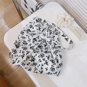 Macro view of floral cotton canvas shoulder bag showing black flower pattern and fabric texture
