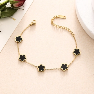 Detail of gold double-layer chain bracelet featuring five black enamel flower charms