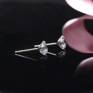 Elegant pair of silver S925 four-claw zircon stud earrings on a dark reflective surface