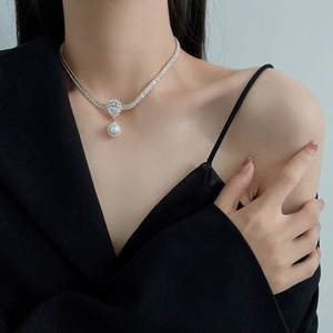Detail of pear-cut zircon necklace with pearl pendant on model for elegant styling