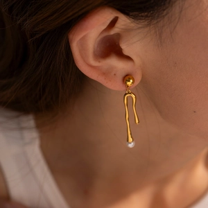 Detail view of 18k gold plated irregular liquid style earrings with white pearl drop