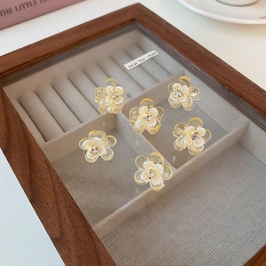 Close-up of small floral hair clips with rhinestones in cream yellow on a wood case