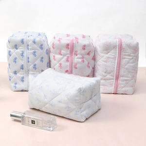 Close-up of quilted cotton cosmetic bags with bow prints and smooth zippers