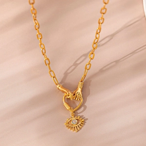 Macro detail of gold devil's eye necklace featuring a heart-shaped hands clasp and blue zircon