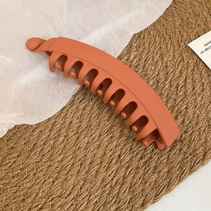 Gros plan d'une pince à cheveux banane rouge orangé mat montrant ses dents imbriquées