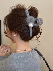 Detailed side view of a plush grey hair claw clip with white pearls and fluffy pom-pom detail