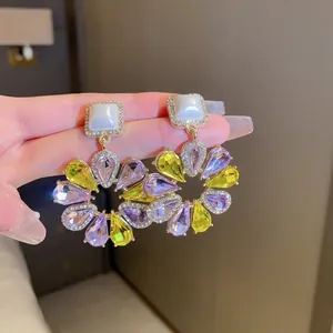 Vintage-Ohrhänger in Blumenform mit lila und gelben Kristallen in der Hand gehalten