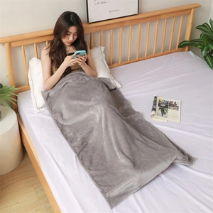 Cozy grey flannel blanket draped over a woman sitting in a minimalist bedroom setting