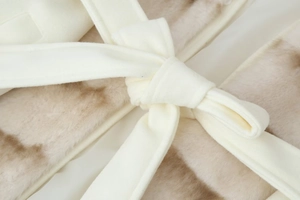 Detail shot of the cream-white waist tie on a stylish beige faux fur wool coat