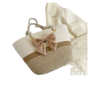 Woven straw tote bag with a khaki bow and hemp rope handles on a white background