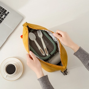 Insulated nylon lunch bag in yellow with lunch box and cutlery set in an office setting