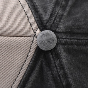 Macro shot of the multi-panel crown stitching and top button on this two-tone cotton cap