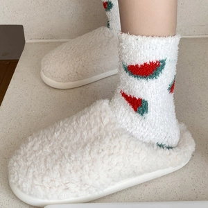 Gros plan de chaussettes en polaire blanche avec motifs pastèque rouges et texture douce