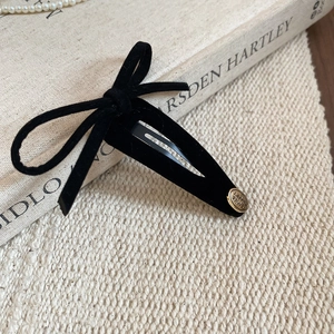 Detail showing black velvet bow hair clip with gold Smile Happy metal charm