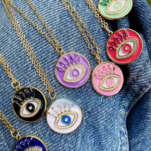 Nahaufnahme bunter Evil Eye Anhänger in Gold-Optik auf einem Jeans-Hintergrund