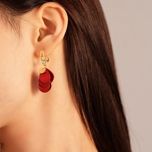 Detail of red acrylic flower petal earrings with gold hook and a sparkling crystal