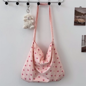 Detailed view of pink heart print canvas tote bag hanging with cute sheep keychain charm