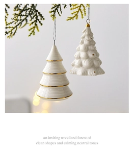 Detail of white ceramic Christmas tree ornaments with gold edges on pine branch