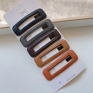 Detailed view of 5-piece PU leather hair clip set in assorted earthy tones on display card