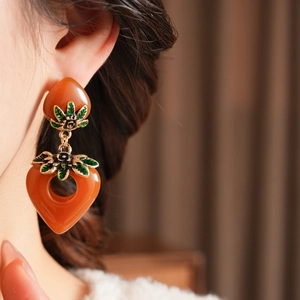 Details von Vintage-Bernstein-Herzohrringen mit Goldakzenten und grünen Emaille-Blättern