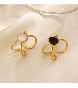 Close-up of gold-plated crossover rings with oval enamel inlay on beige satin fabric