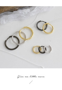 Detail view of hoop earrings in gold silver and black finishes on a textured background