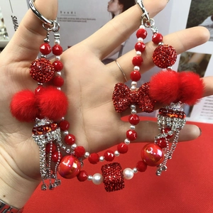 Detail of a red beaded keychain with luxury faux fur ball and rhinestone bow decor