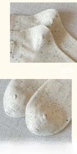 Macro detail of reinforced heel and seamless toe on cream speckled knit socks