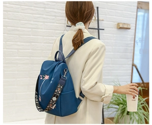 Detailaufnahme des blauen wasserfesten Rucksacks mit Blumenstickerei und Jacquard-Gurt