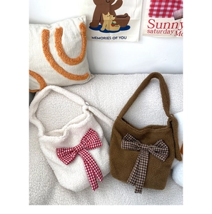 Detailed close-up of plush lamb wool shoulder bags in beige and brown with plaid bows