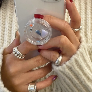 Minimalist 925 sterling silver beaded rings and transparent phone grip on knit background