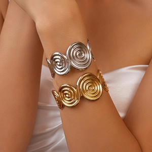 Close-up of gold and silver textured spiral cuff bracelets worn on a model's forearm