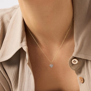 Elegant gold heart pendant necklace with shimmering pave zircons worn by model