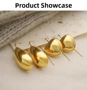 Detail of 18K gold teardrop and triangular earrings on soft textured fabric background
