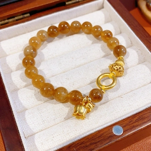 Dettaglio del bracciale con perline di citrino giallo e ciondoli a campana su legno