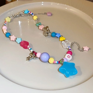 Detail of colorful baroque pearl bead necklace with metallic star and bow pendants