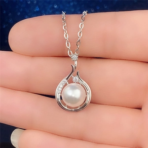Macro detail of Baroque faux pearl pendant with silver metal and zircon inlay on hand