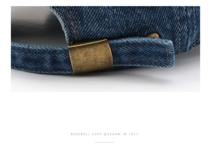 Detailed macro view of an adjustable bronze metal buckle on a navy denim baseball cap